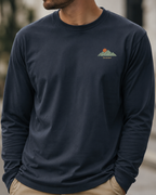 Navy long-sleeve shirt with a logo on a blurred outdoor background