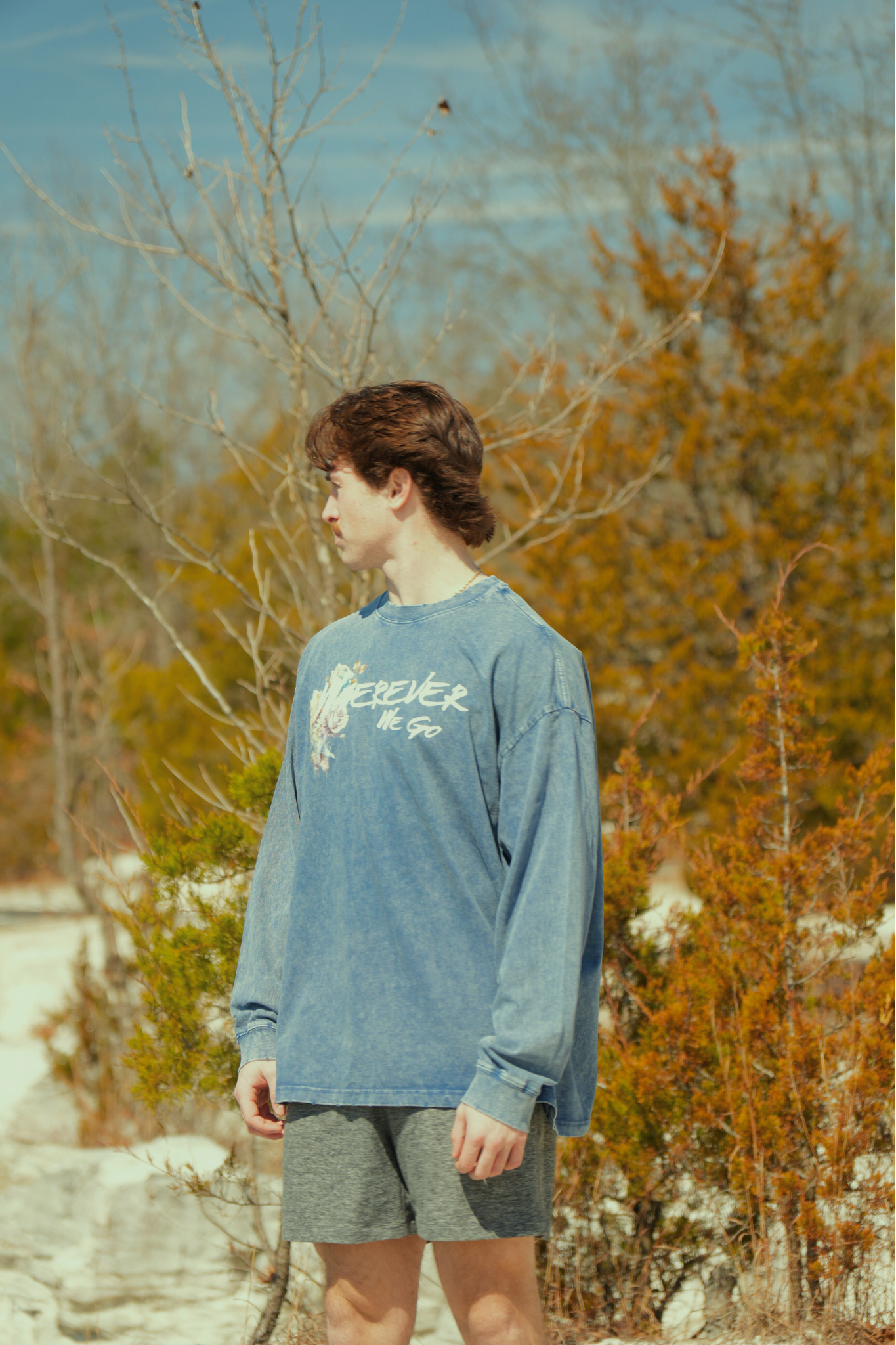 Person wearing a blue sweatshirt with text and graphics outdoors in nature while traveling
